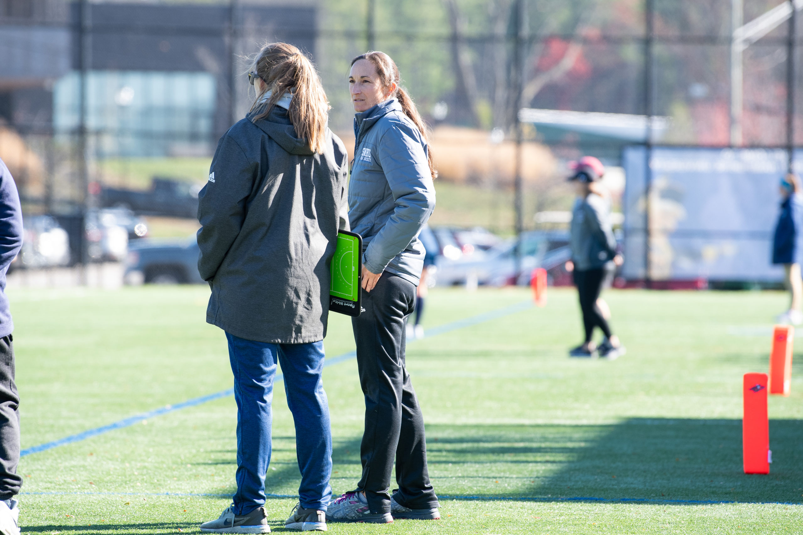 two field hockey coaches talking to one another